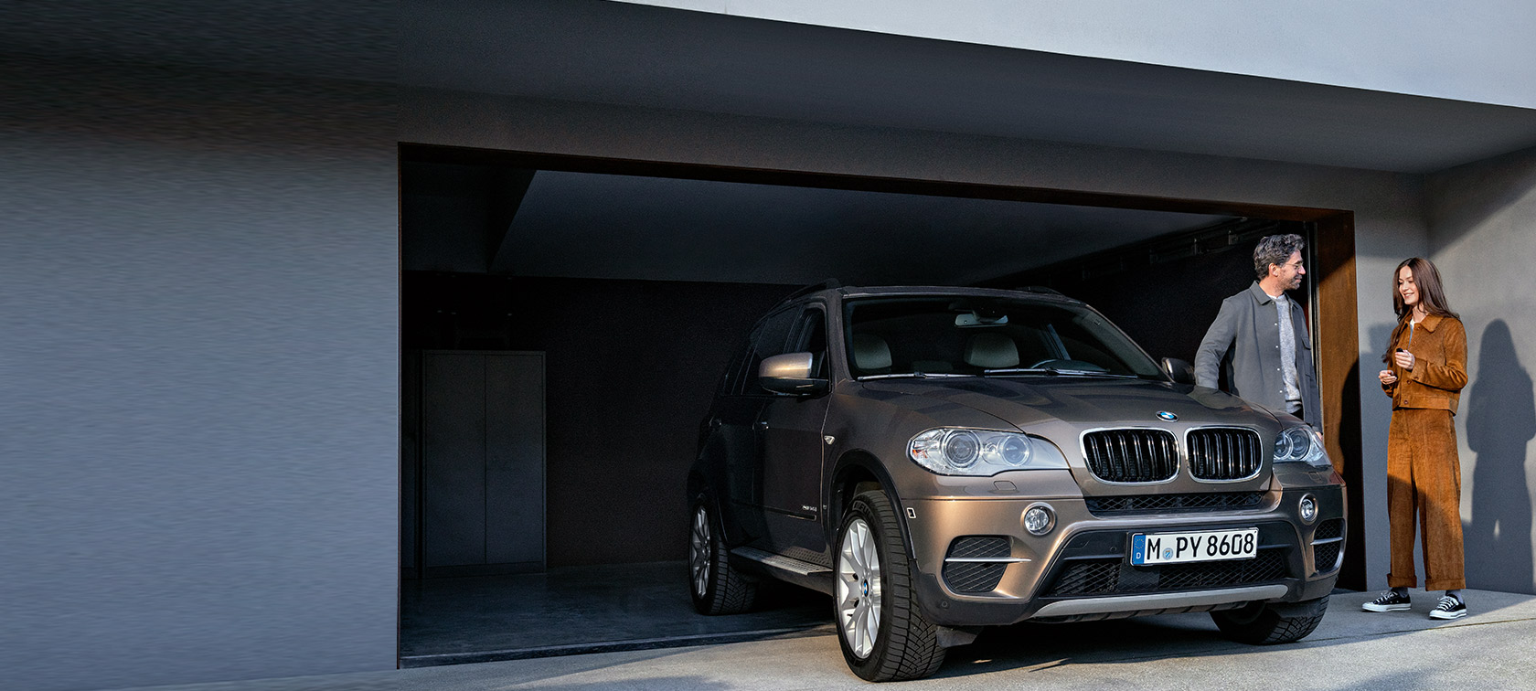 BMW Value Service man and woman in front of garage with BMW X5